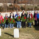 women holding wreaths in front of grave markers at Jefferson Barracks