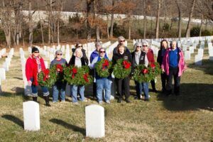 women holding wreaths in front of grave markers at Jefferson Barracks