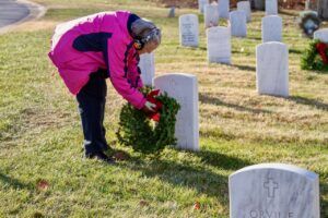 Woman placing wreath on grave marker