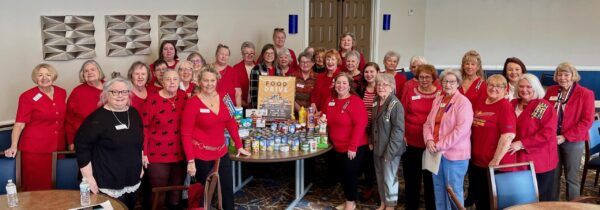three dozen women dressed in red around food pantry collection